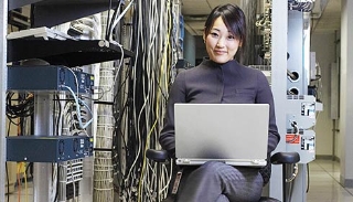 Female IT professional using her laptop while sitting in a server room