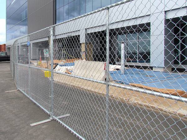 Temporary chain link fence with flat fence feet installed to secure the building construction site.