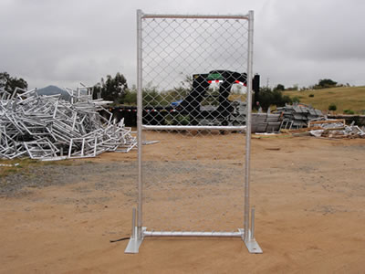 A galvanized chain link temporary fence gate on the ground. The gate has a middle reinforced pipe.