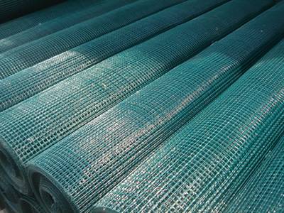 Dark-green PVC coated welded wire mesh rolls lying on the ground