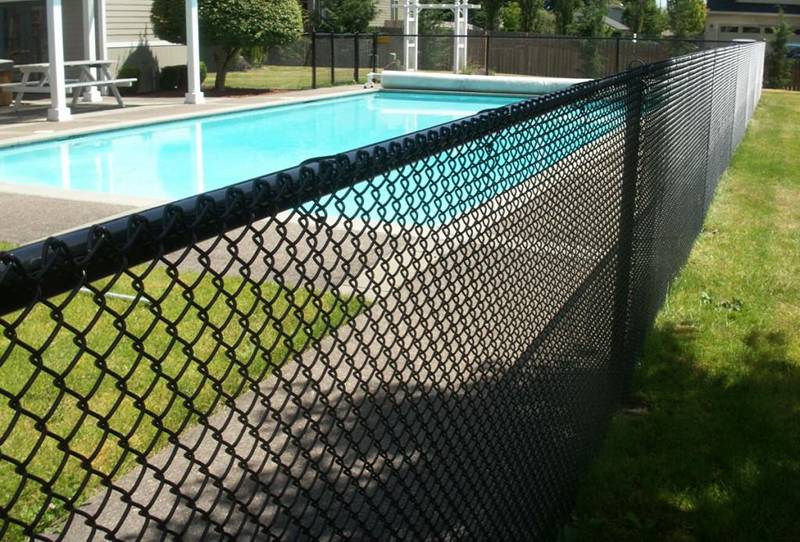 Black vinyl-coated chain link swimming pool fence.