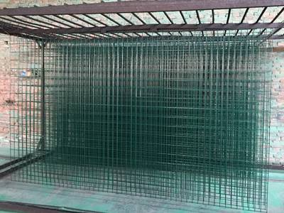 Green PVC coated welded wire panels are hanging up waiting to dry