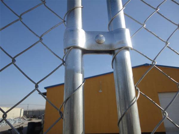 A close up picture of galvanized clamp installed to connect the two temporary chain link fence panels.