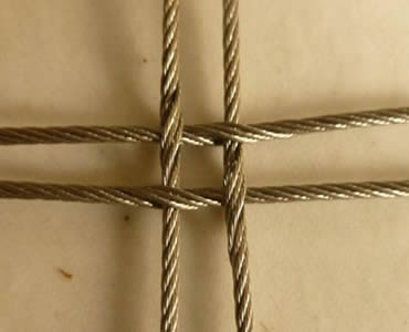 A piece of cross-shaped stainless steel square rope mesh is on the floor.