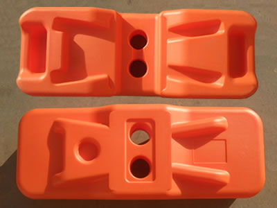 Two orange blow moulded temporary fence feet on the floor. We can see their positive and back sides.