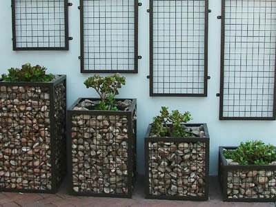 Four welded gabion with different height on the ground with plants in the pot.
