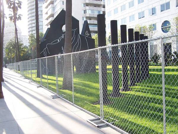Temporary chain link fence with square tubular fence feet installed by the roadside.