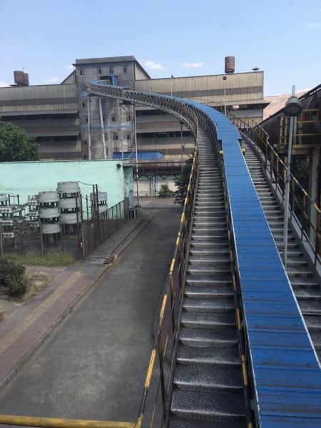 Sistema de transporte por cinta de tubería para el transporte cerrado de material a granel libre de polvo curvado