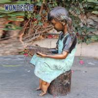 China Custom Life Size A bronze statue of a girl reading on a tree stump on sale